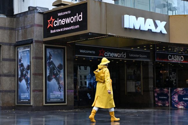 A passer-by wrapped up against the rain walks past a Cineworld cinema in Leicester Square in central London, on 4 October 2020 (AFP)